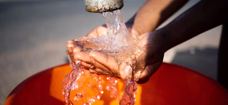 african-woman-pouring-water-recipient-outdoors_23-2149021909