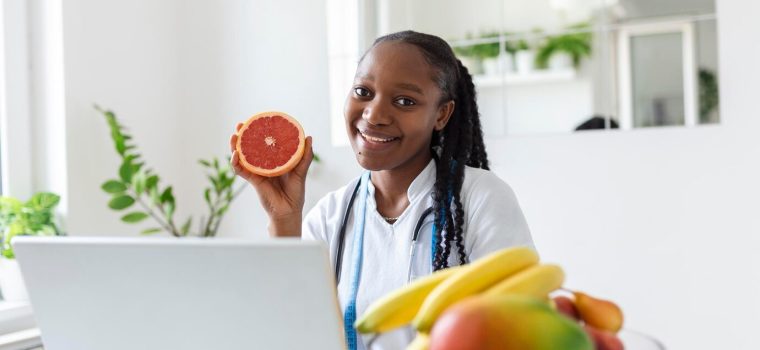 portrait-young-smiling-female-nutritionist-consultation-room-nutritionist-desk-with-healthy-fruit-juice-measuring-tape-dietitian-working-diet-plan_657921-985
